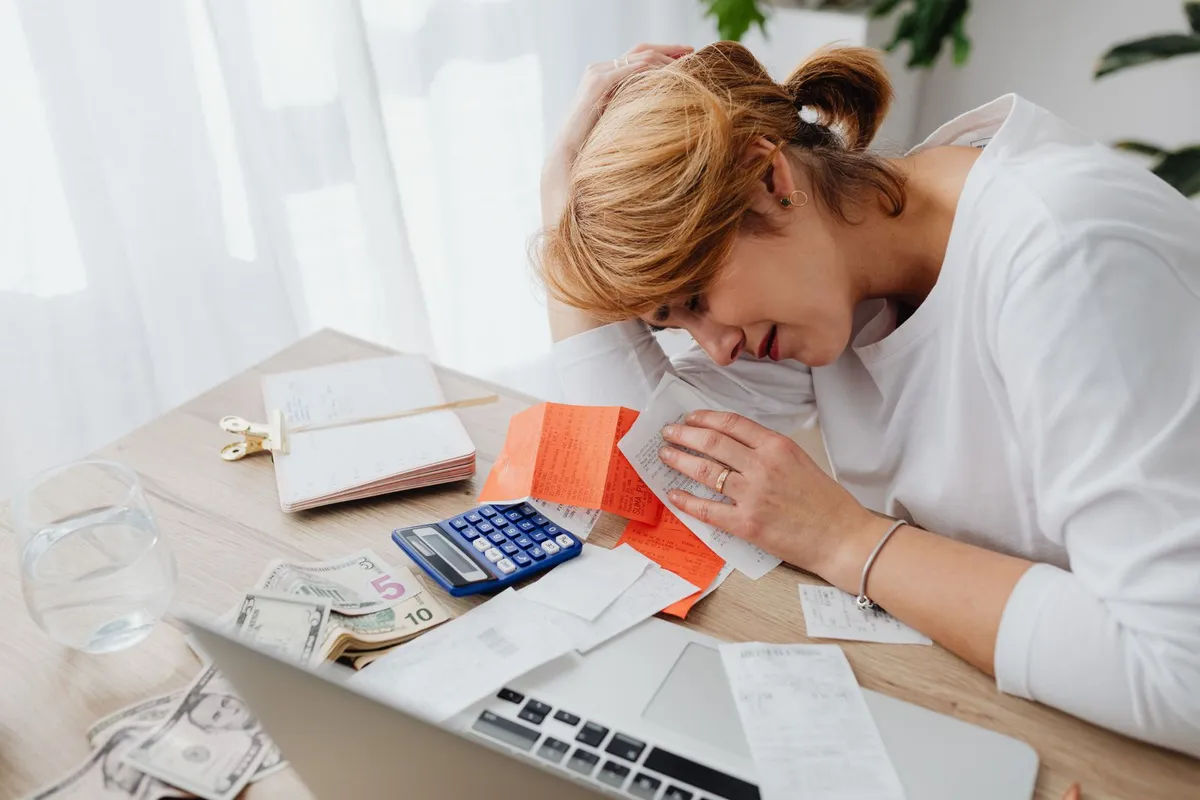 Person overwhelmed by bills and financial paperwork before filing for bankruptcy